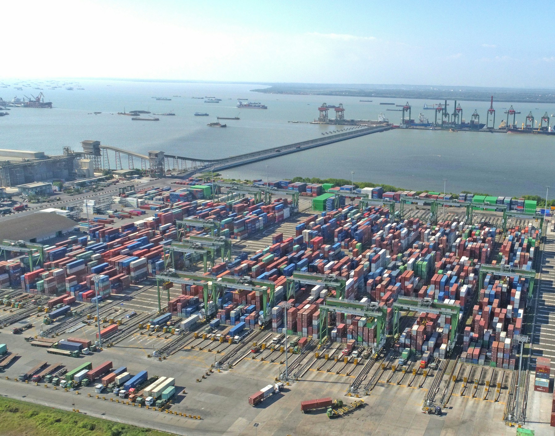 Aerial view of container stacks, cranes and ships across a large port.